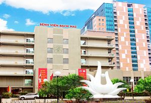 Front view of Bach Mai Hospital in Hanoi, showcasing modern buildings and the iconic white sculpture at the main entrance.