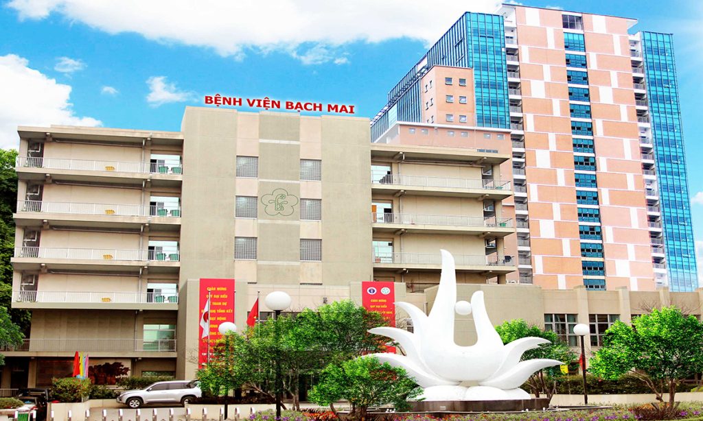 Front view of Bach Mai Hospital in Hanoi, showcasing modern buildings and the iconic white sculpture at the main entrance.