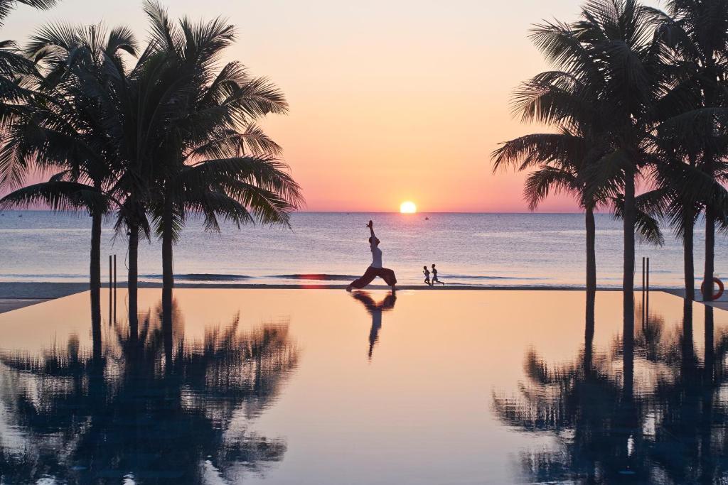 Wellness Retreats in Vietnam with sunrise beach yoga session at a luxury resort surrounded by palm trees and ocean views